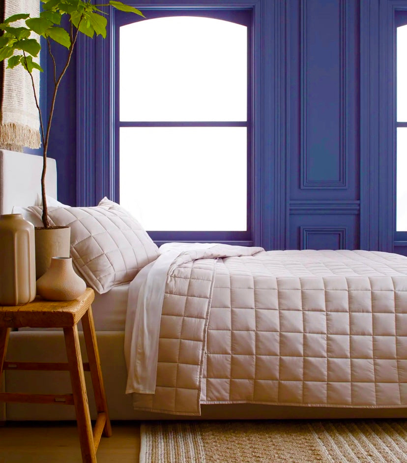 Cubrecama quilt de algodón beige sobre cama iluminada con luz natural