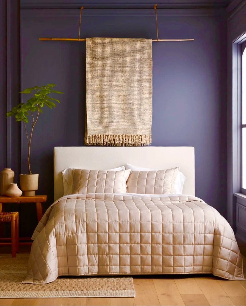 Cubrecama quilt de algodón beige sobre cama doble en habitación decorada